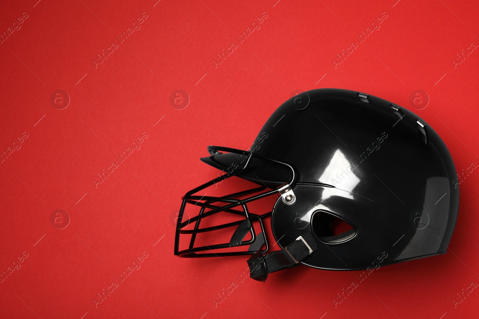 Photo of Black baseball helmet on red background, top view. Space for text