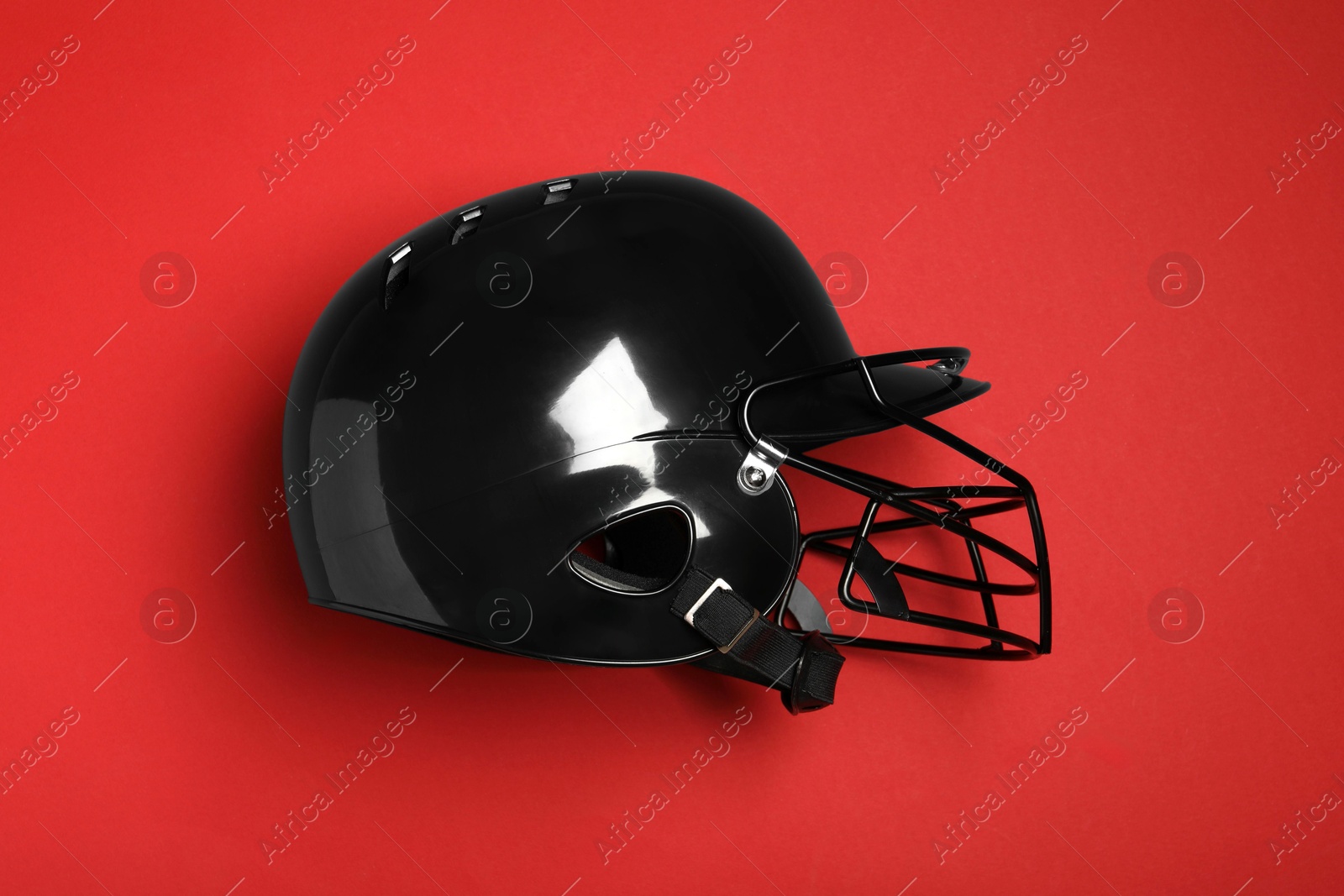 Photo of Black baseball helmet on red background, top view