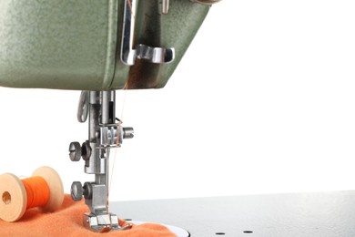 Photo of Sewing machine with orange fabric and spool of thread isolated on white