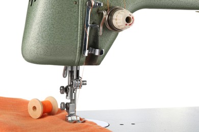 Photo of Sewing machine with orange fabric and spool of thread isolated on white