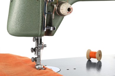 Photo of Sewing machine with orange fabric and spool of thread isolated on white