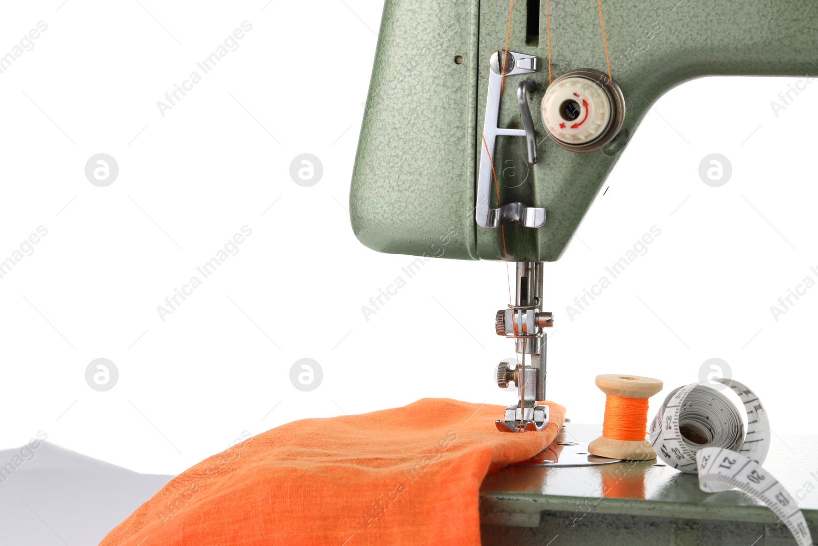 Photo of Sewing machine with orange fabric, measuring tape and spool of thread isolated on white