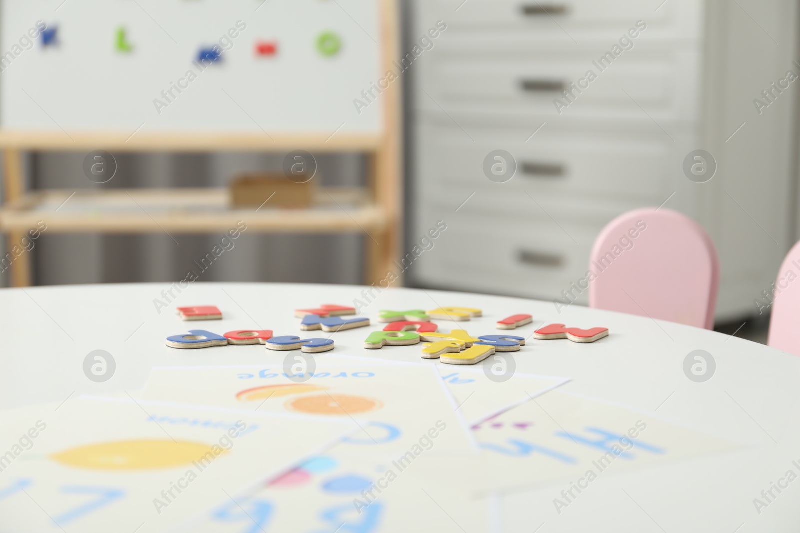 Photo of Learning alphabet. Different magnetic letters and pictures on white table indoors