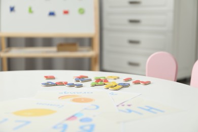 Photo of Learning alphabet. Different magnetic letters and pictures on white table indoors