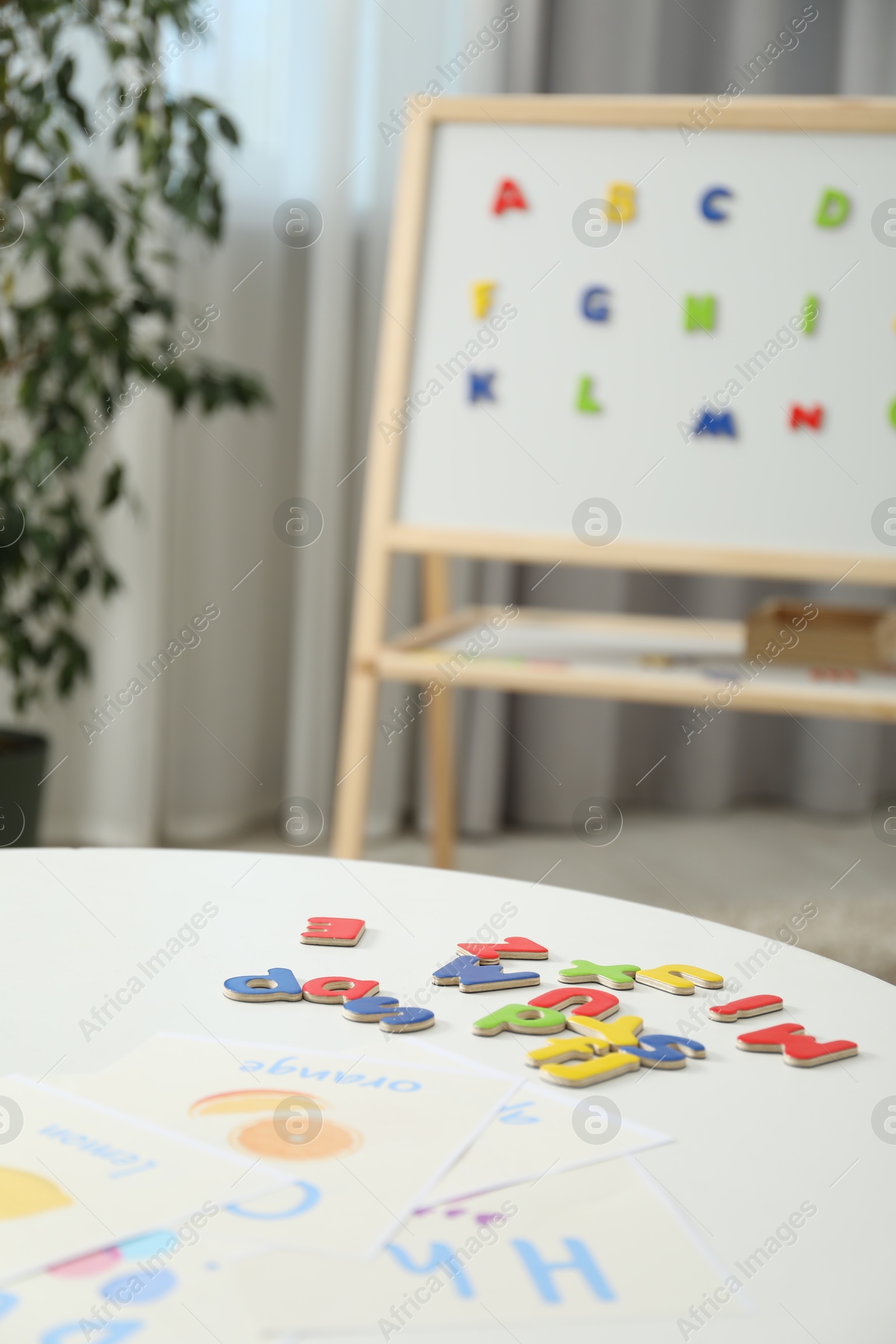 Photo of Learning alphabet. Different magnetic letters and pictures on white table indoors