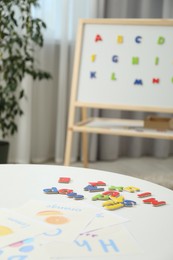 Photo of Learning alphabet. Different magnetic letters and pictures on white table indoors