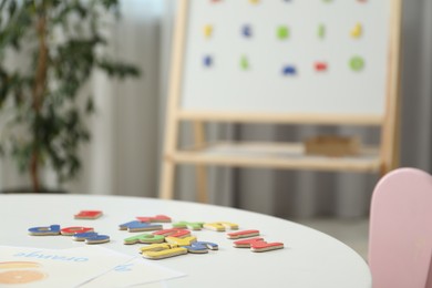 Photo of Learning alphabet. Different magnetic letters and pictures on white table indoors