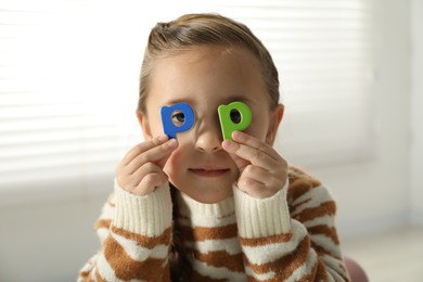 Photo of Learning alphabet. Little girl closing eyes with magnetic letters P indoors