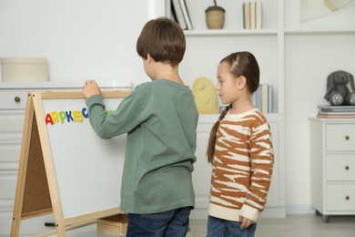 Photo of Little kids learning alphabet with magnetic letters indoors