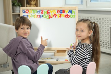 Photo of Little kids learning alphabet with magnetic letters indoors