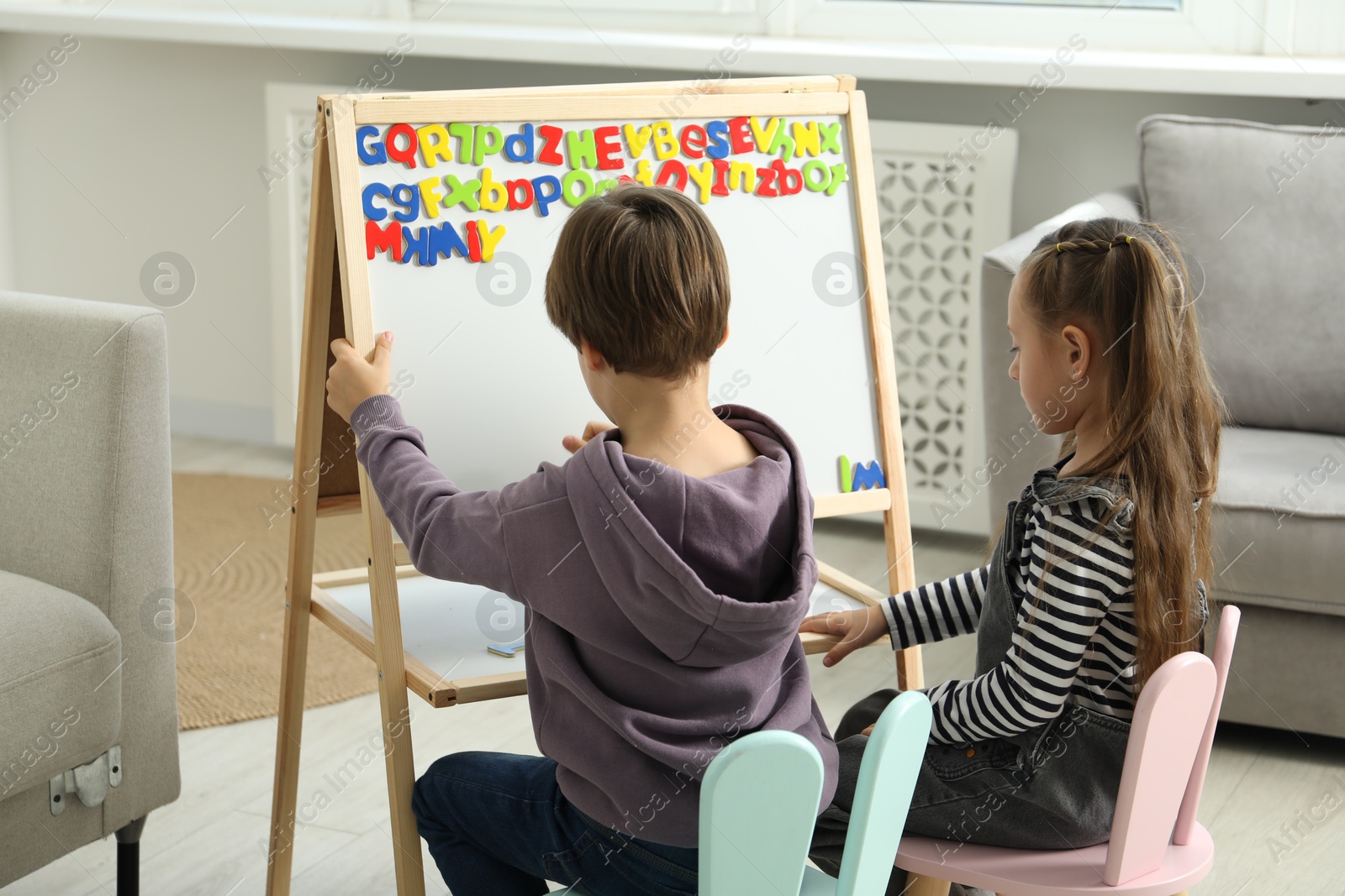 Photo of Little kids learning alphabet with magnetic letters indoors