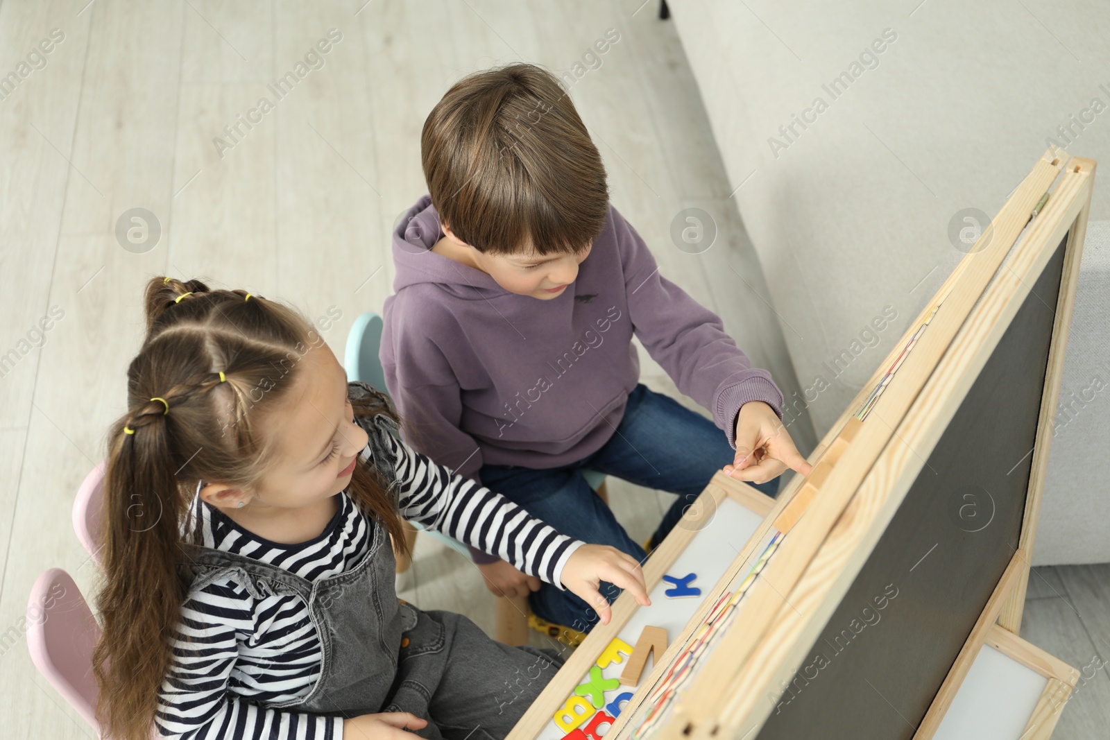 Photo of Little kids learning alphabet with different letters on board indoors