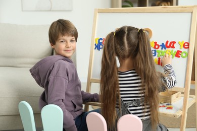 Photo of Little kids learning alphabet with different letters on board indoors