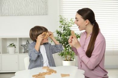 Speech therapist teaching little boy alphabet with wooden letters at white table indoors