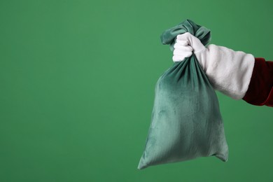 Photo of Santa Claus with bag of Christmas gifts on green background, closeup. Space for text