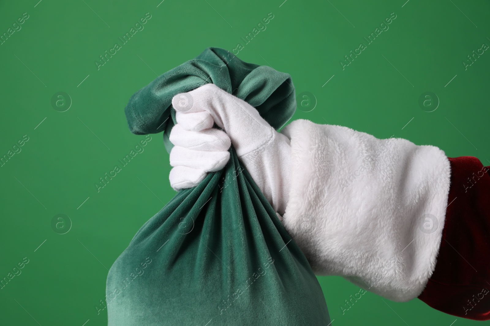 Photo of Santa Claus with bag of Christmas gifts on green background, closeup