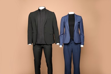 Female and male mannequins with stylish suits on light brown background