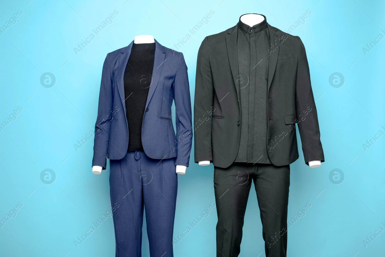 Photo of Female and male mannequins with stylish suits on light blue background