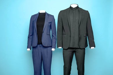 Photo of Female and male mannequins with stylish suits on light blue background