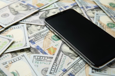 Photo of Modern smartphone on dollar bills, closeup view