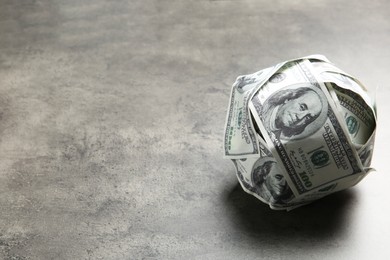 Photo of Ball made of dollars on grey table. Space for text