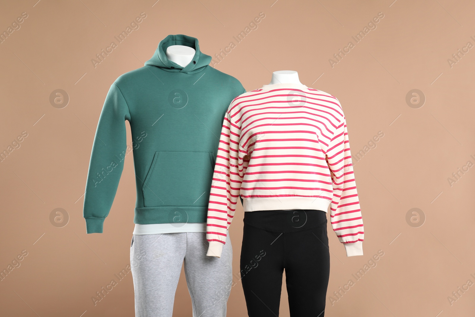 Photo of Female and male mannequins with stylish outfits on beige background