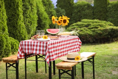 Photo of Fresh fruits, pie and vase with sunflowers on table in garden