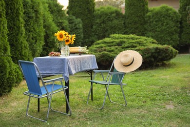 Photo of Vase of sunflowers, corn and grapes on table in garden