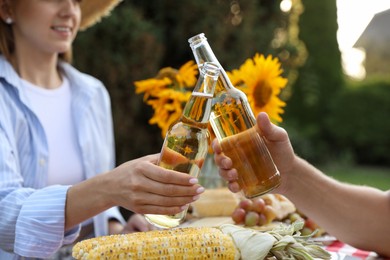 Photo of Friends with drinks enjoying picnic at table in garden, closeup