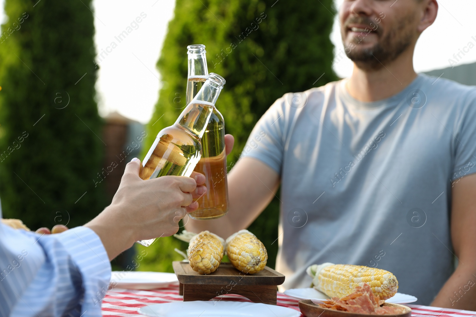 Photo of Friends with drinks enjoying picnic at table in garden, closeup