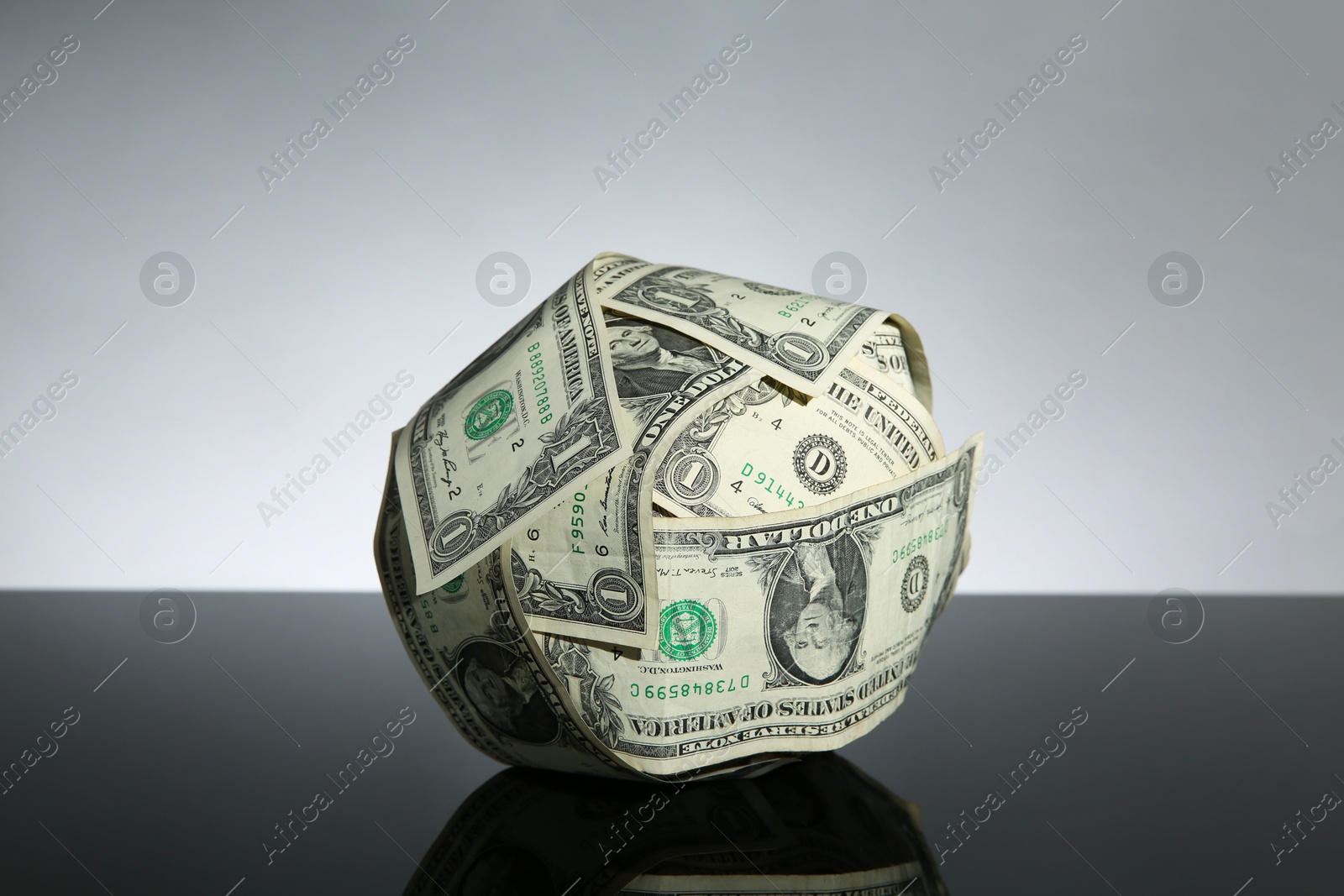 Photo of Ball made of dollars on black mirror surface