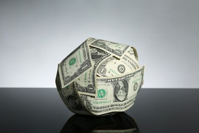 Photo of Ball made of dollars on black mirror surface