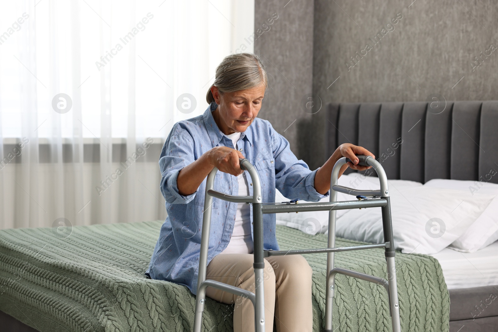 Photo of Senior woman with walking frame on bed at home