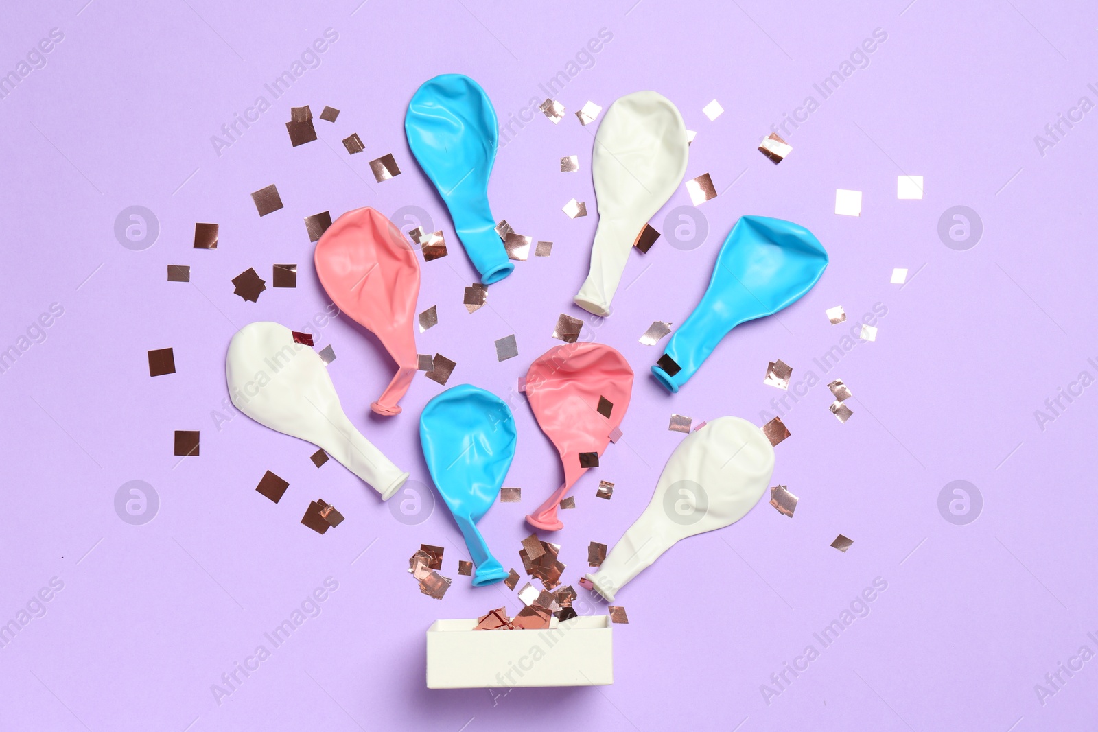 Photo of Shiny confetti and deflated balloons flying out of little box on violet background, flat lay