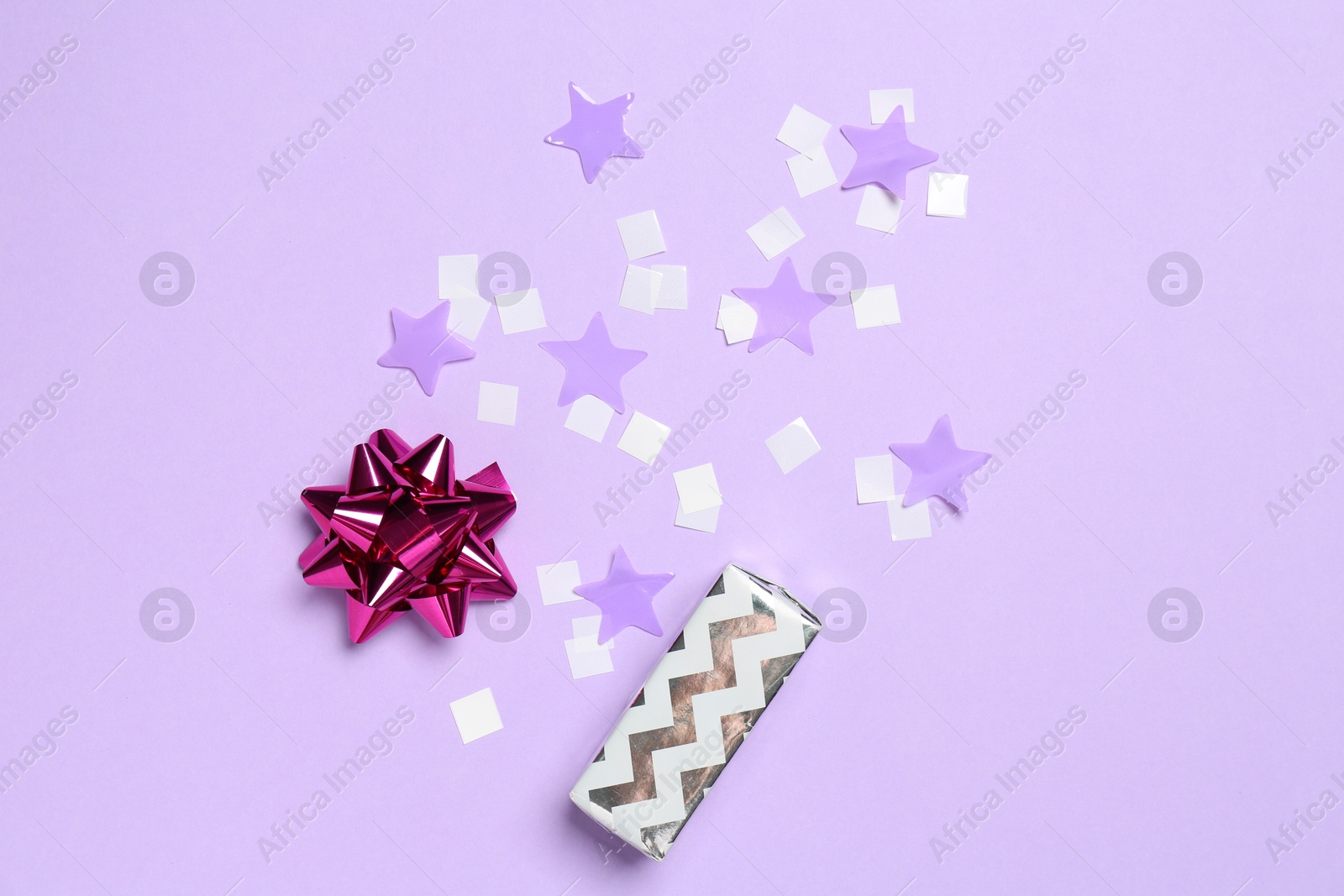 Photo of Shiny confetti and festive decor on violet background, flat lay