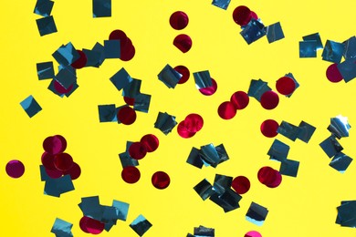 Photo of Shiny confetti on yellow background, top view