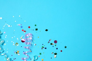 Photo of Shiny confetti and party streamers on light blue background, flat lay. Space for text