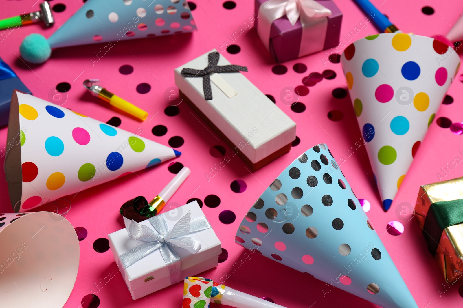 Photo of Shiny confetti and party decor on pink background, closeup