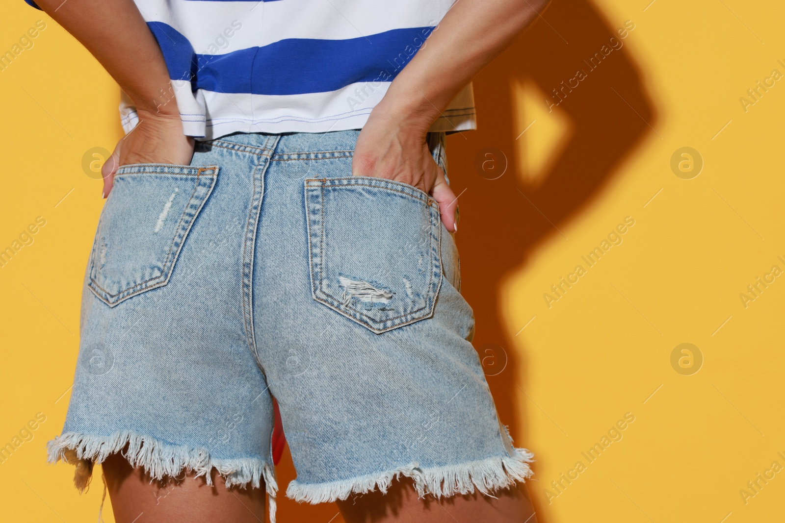 Photo of Woman wearing stylish denim shorts on yellow background, closeup. Space for text