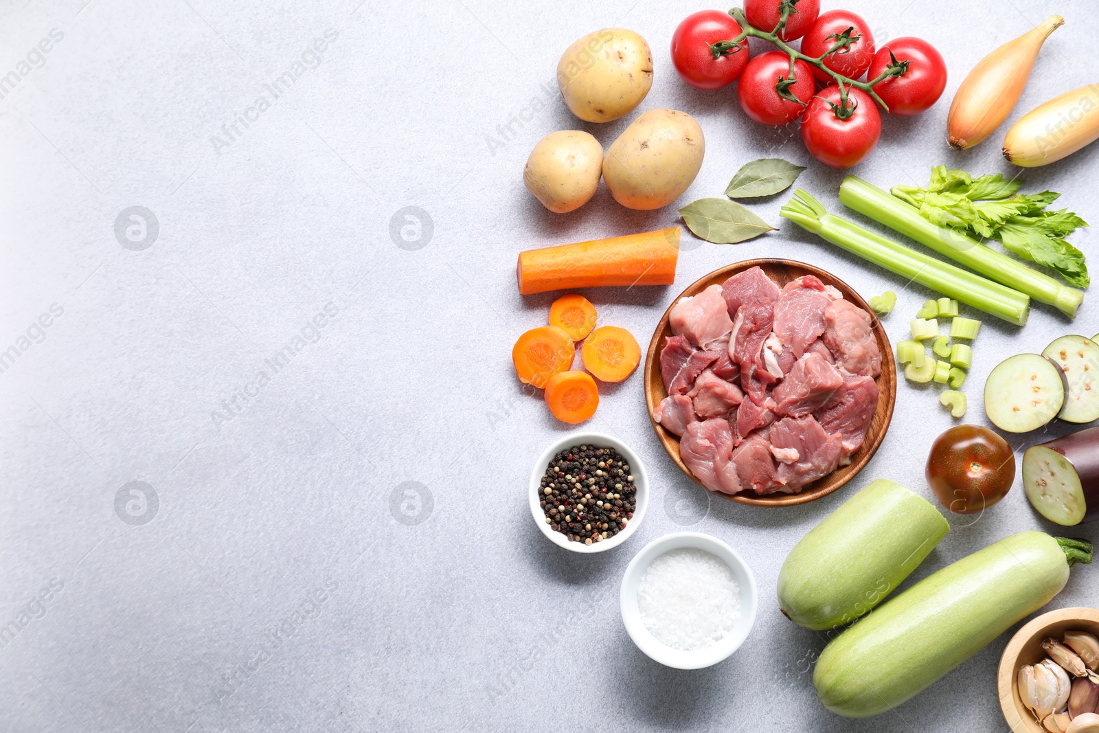 Photo of Cooking stew. Uncooked meat and vegetables on light grey table, flat lay. Space for text