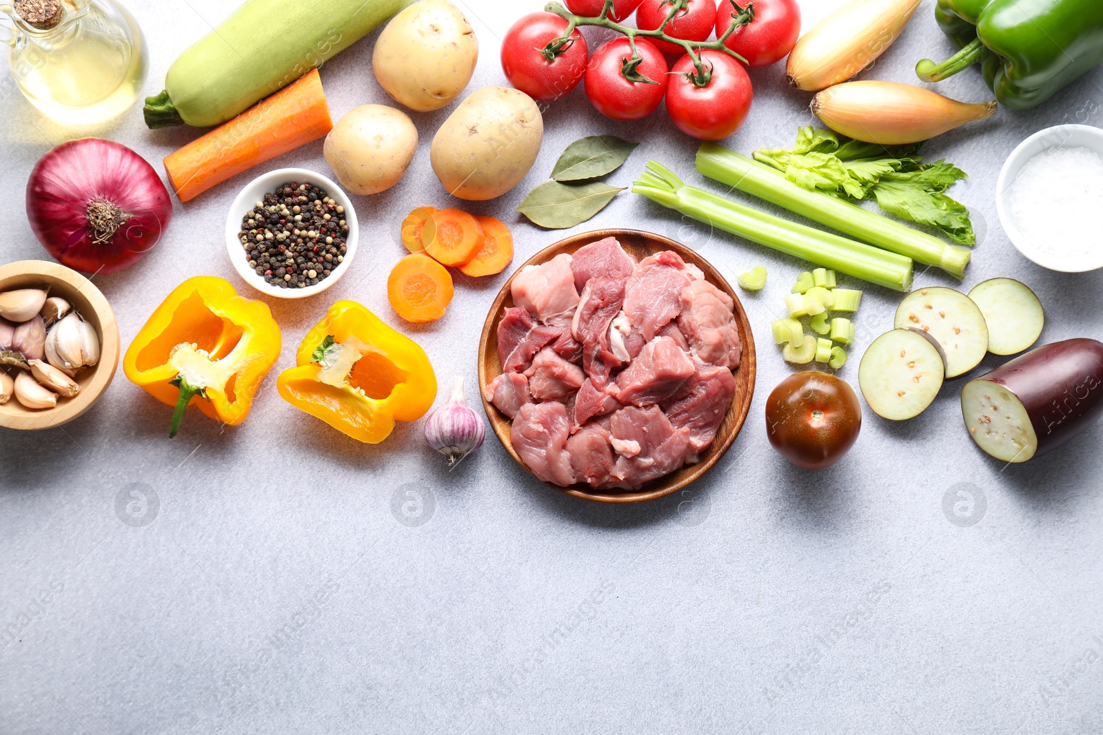 Photo of Cooking stew. Uncooked meat and vegetables on light grey table, flat lay. Space for text