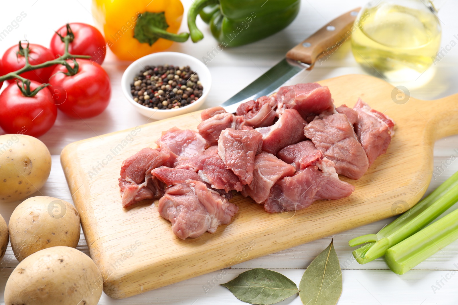 Photo of Cooking stew. Uncooked meat and vegetables on white wooden table