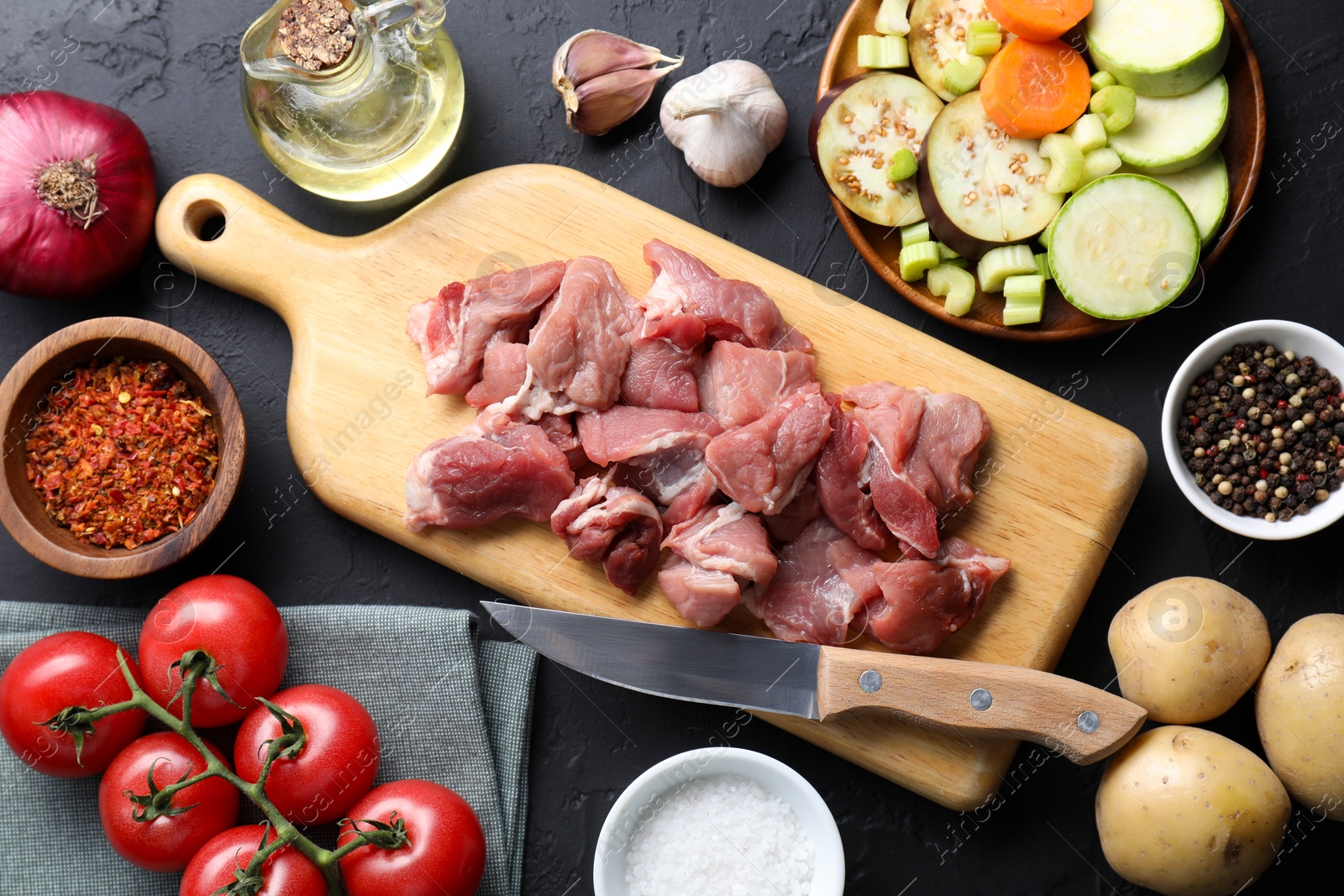 Photo of Cooking stew. Uncooked meat and vegetables on black table, flat lay