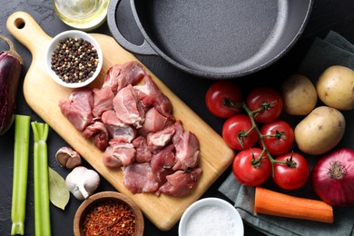 Photo of Cooking stew. Uncooked meat, vegetables and pot on black table, flat lay