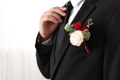 Photo of Groom in suit with stylish boutonniere indoors, closeup