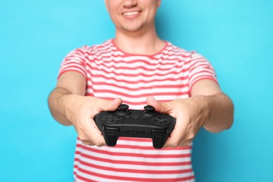 Photo of Man playing video games with controller on light blue background, closeup