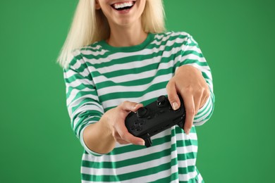 Woman playing video games with controller on green background, closeup