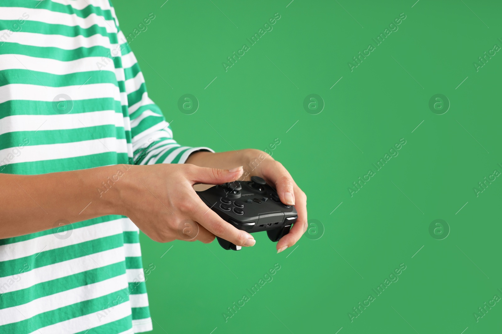 Photo of Woman playing video games with controller on green background, closeup. Space for text