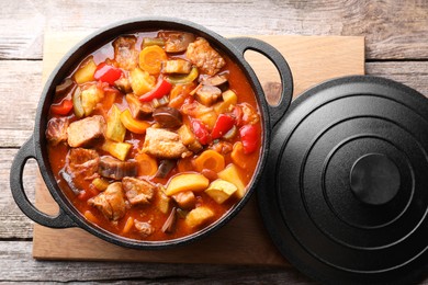 Photo of Delicious stew with vegetables in pot on wooden table, top view