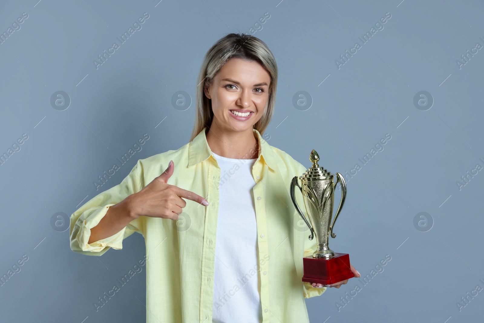 Photo of Happy winner with golden trophy cup on gray background,